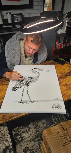 Zechariah working on a heron drawing under studio light